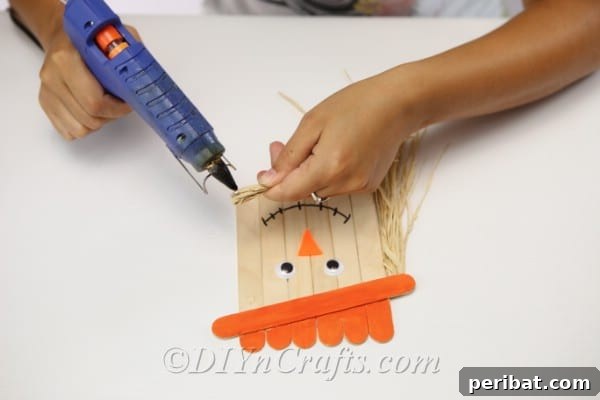 Gluing the twine or hay onto the scarecrow head