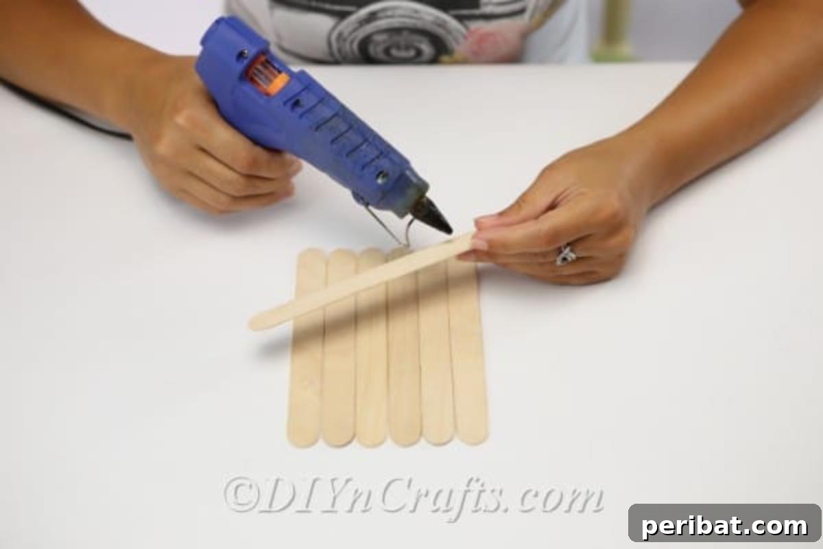 Gluing craft sticks together to create a scarecrow head