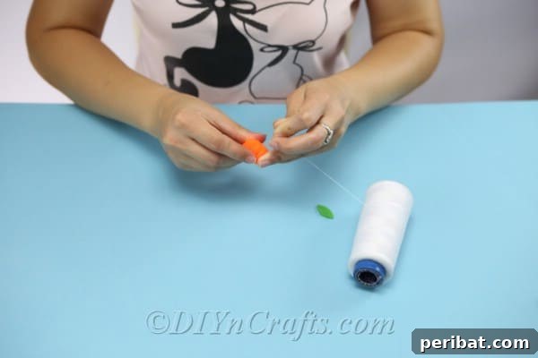 Craft Charming Pumpkin Gift Boxes 13 Wrapping an orange pom-pom with thread to create a textured pumpkin stem for the DIY gift box