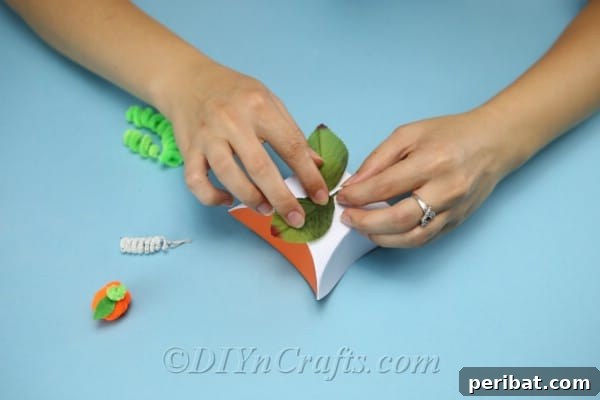 Craft Charming Pumpkin Gift Boxes 14 Gluing artificial leaves to the top of the cardstock box to enhance the pumpkin theme