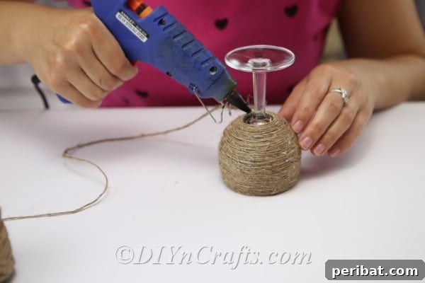 Rustic Glow: DIY Wine Glass Candle Holder 9 The twine wrapping extends down the stem of the wine glass, showing progression towards the base.