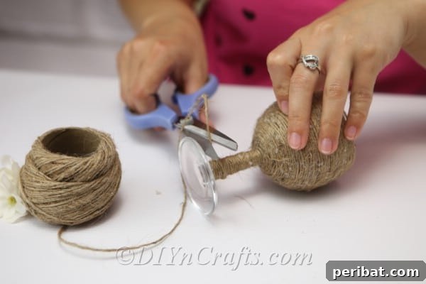 Rustic Glow: DIY Wine Glass Candle Holder 10 Cutting the excess twine once the entire wine glass, excluding the foot, has been covered.