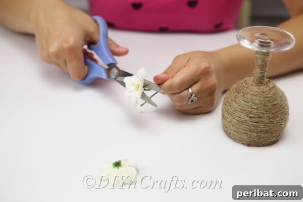 Rustic Glow: DIY Wine Glass Candle Holder 12 Preparing faux flowers by cutting them to the appropriate size for attaching to the candle holder.