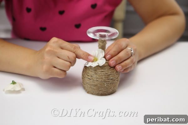 Rustic Glow: DIY Wine Glass Candle Holder 14 A cluster of faux flowers beautifully glued onto the rustic candle holder, adding a pop of color and texture.