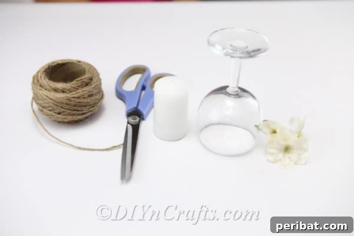 Rustic Glow: DIY Wine Glass Candle Holder 4 A collection of supplies neatly arranged for making the rustic candle holder: a wine glass, a roll of twine, a hot glue gun, scissors, faux flowers, and a pillar candle.
