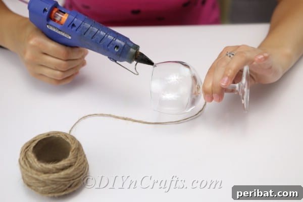 Rustic Glow: DIY Wine Glass Candle Holder 6 Applying hot glue to the rim of a wine glass before starting the twine wrapping process.