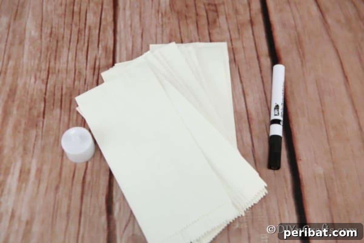 DIY Ghostly Glow Bags for Halloween 5 Supplies for Halloween ghost luminary bags laid out on a table: white bags, marker, tealights