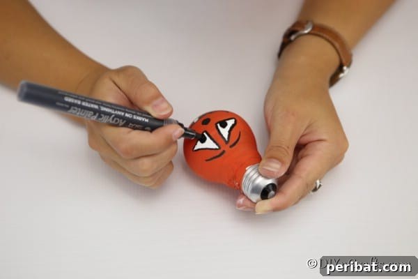 Painting a face on the pumpkin decorative light bulbs