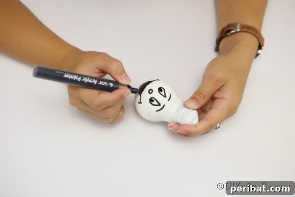 Crafting Spooky Ghosts and Pumpkins from Light Bulbs 15 Painting a face on the ghost decorative light bulbs