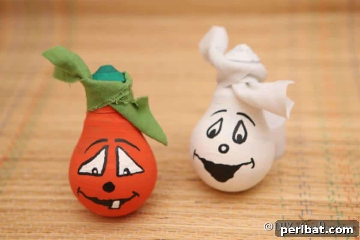 Crafting Spooky Ghosts and Pumpkins from Light Bulbs 5 Two completed Halloween decorative light bulbs sitting on tan cloth, one ghost and one pumpkin