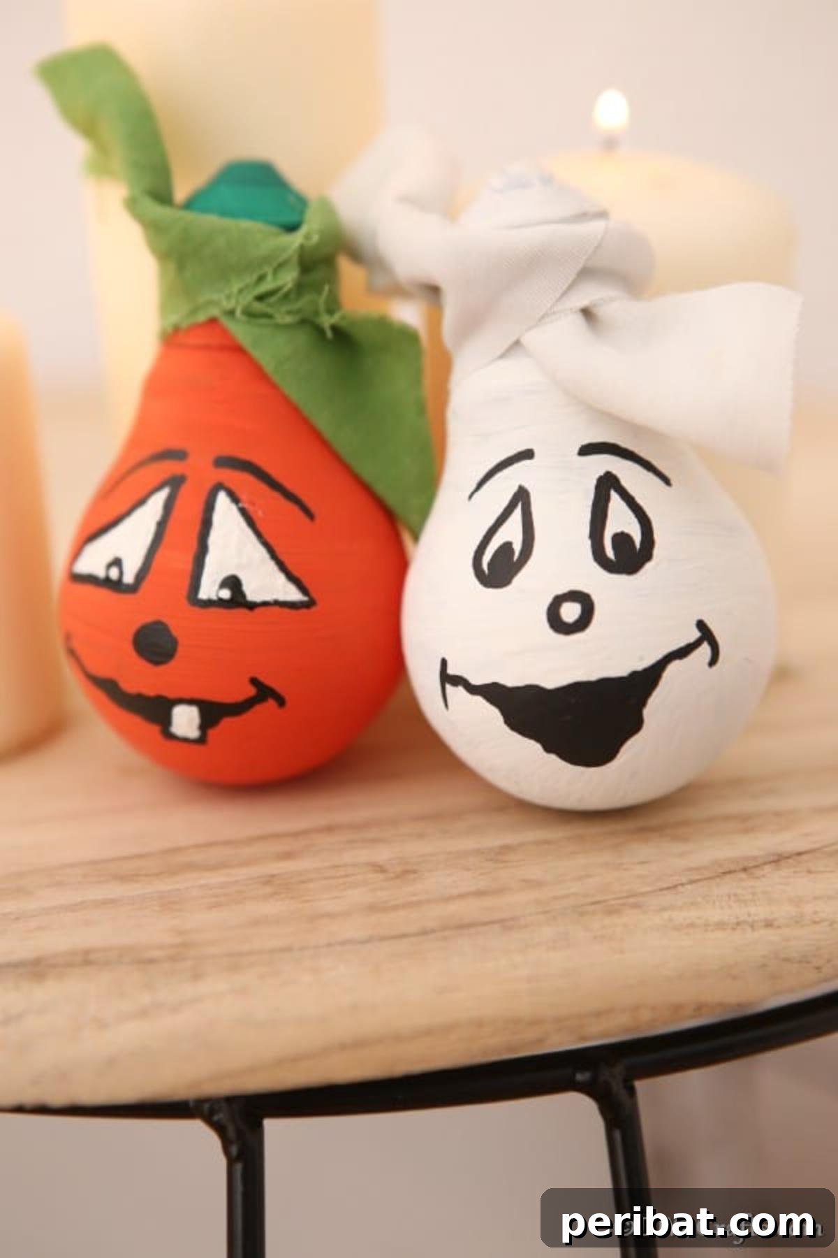Crafting Spooky Ghosts and Pumpkins from Light Bulbs 10 Two decorative light bulbs decorated for Halloween sitting on a wooden stool, one ghost and one pumpkin