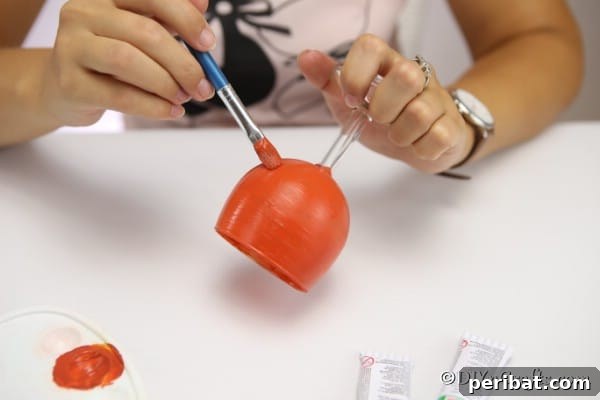A woman finishing painting the wine glass to create a pumpkin art piece