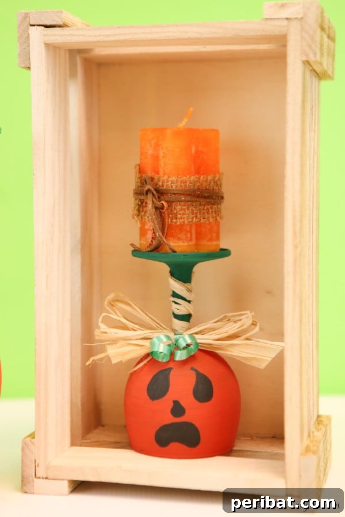 A single, beautifully crafted wine glass pumpkin art piece nestled within a rustic wooden box display, adding warmth to fall decor.