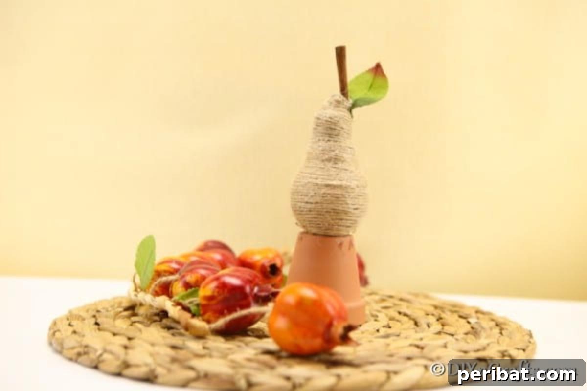 Handcrafted Twine Pear Bulb Art 3 A twine wrapped pear fruit decoration sitting on a woven mat