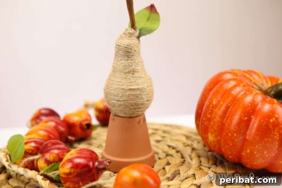 Handcrafted Twine Pear Bulb Art 6 A wrapped pear fruit decoration sitting on top of a small terra cotta planter