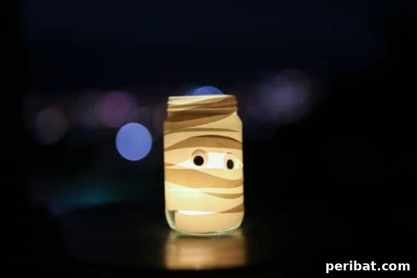 A completed DIY Mummy Mason Jar Light with glowing googly eyes, ready for Halloween decoration.