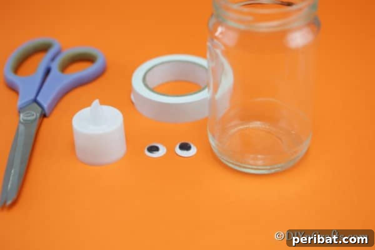 A flat lay photograph showcasing all the supplies needed for the mummy mason jar light craft: a jar, paper tape, googly eyes, scissors, and a hot glue gun.