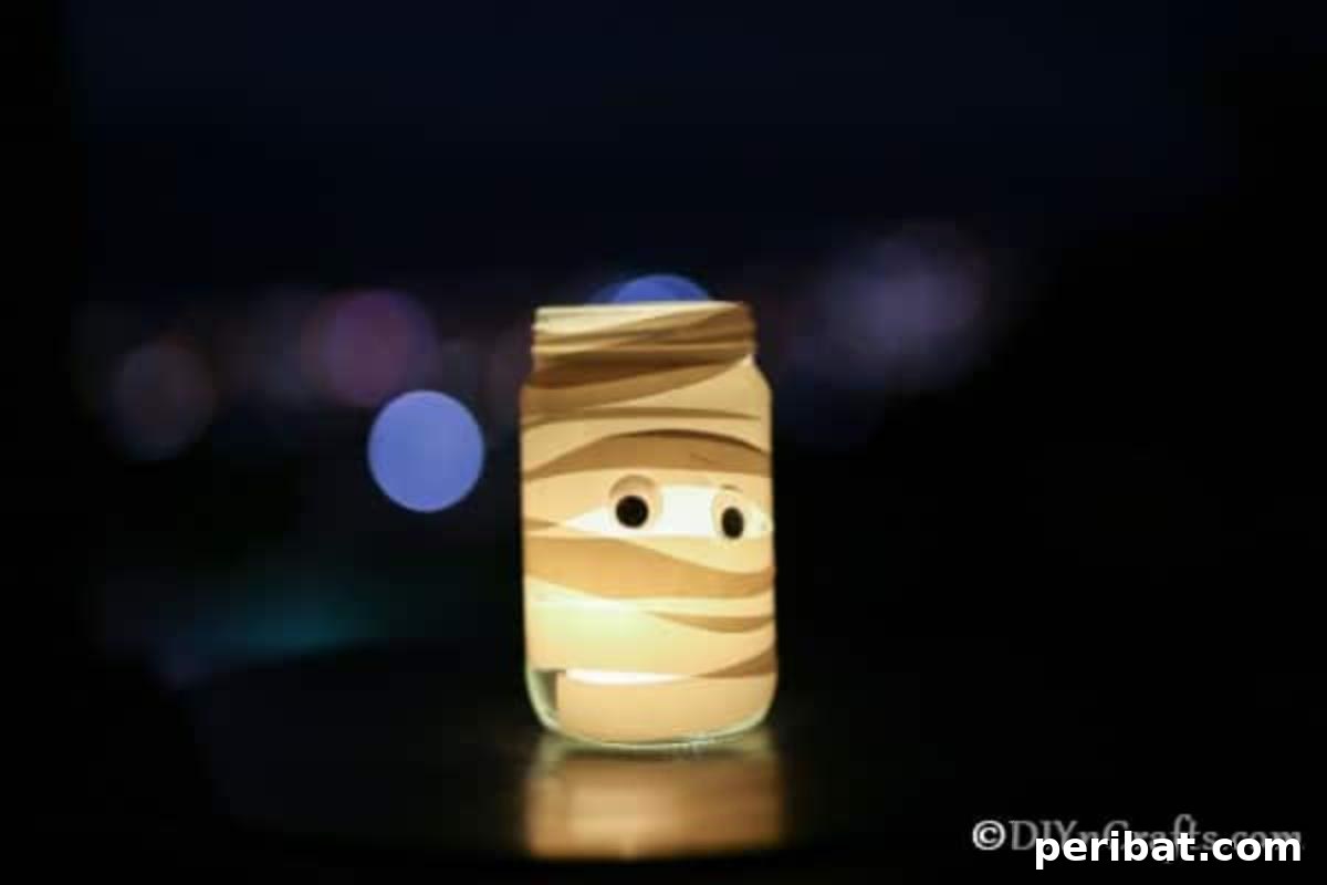 A fully wrapped mummy mason jar light with googly eyes, glowing with a tealight inside, sitting on a dark surface in a minimalist setting.