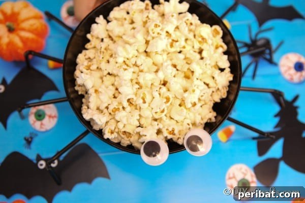 Halloween Spider Web Treat Bowl DIY 17 Overhead picture of halloween spider bowl on a blue surface and filled with popcorn