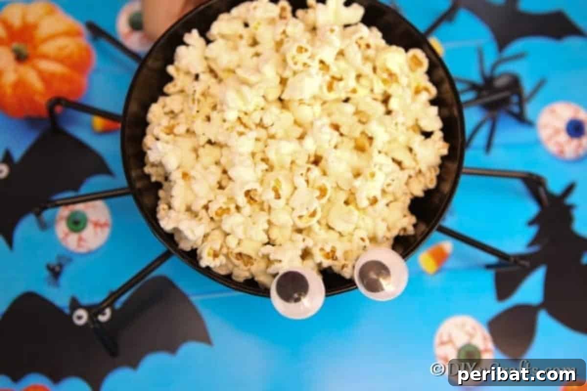 Halloween Spider Web Treat Bowl DIY 9 Overhead picture of halloween spider bowl on a blue surface and filled with popcorn