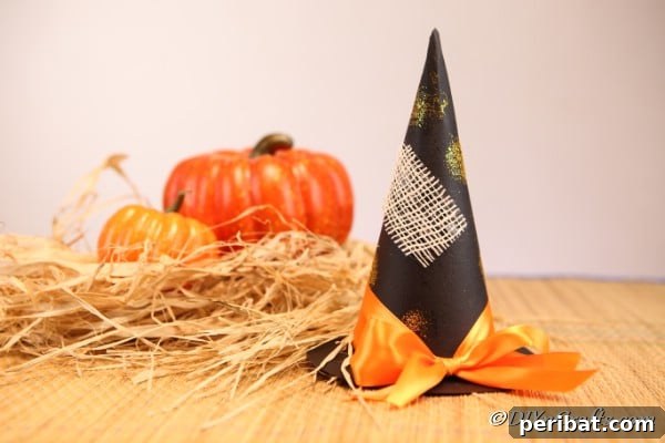 Witch hat displayed on brown cloth next to mini pumpkins, a perfect DIY Halloween decoration