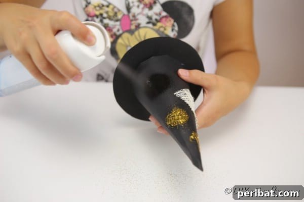 Bewitching DIY Witch Hat for Halloween 17 Spraying glitter onto the witch hat decoration