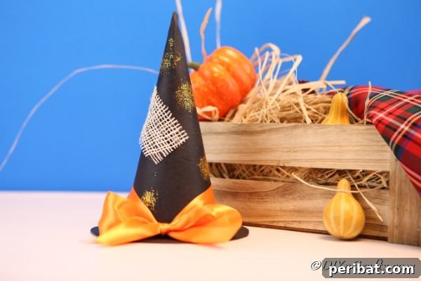 Bewitching DIY Witch Hat for Halloween 21 Witch hat sitting on counter in front of a wooden basket filled with hay and mini pumpkins