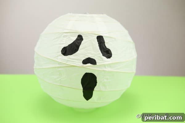 Hauntingly Simple Ghost Lanterns 13 A completed ghost paper lantern sitting on a green surface