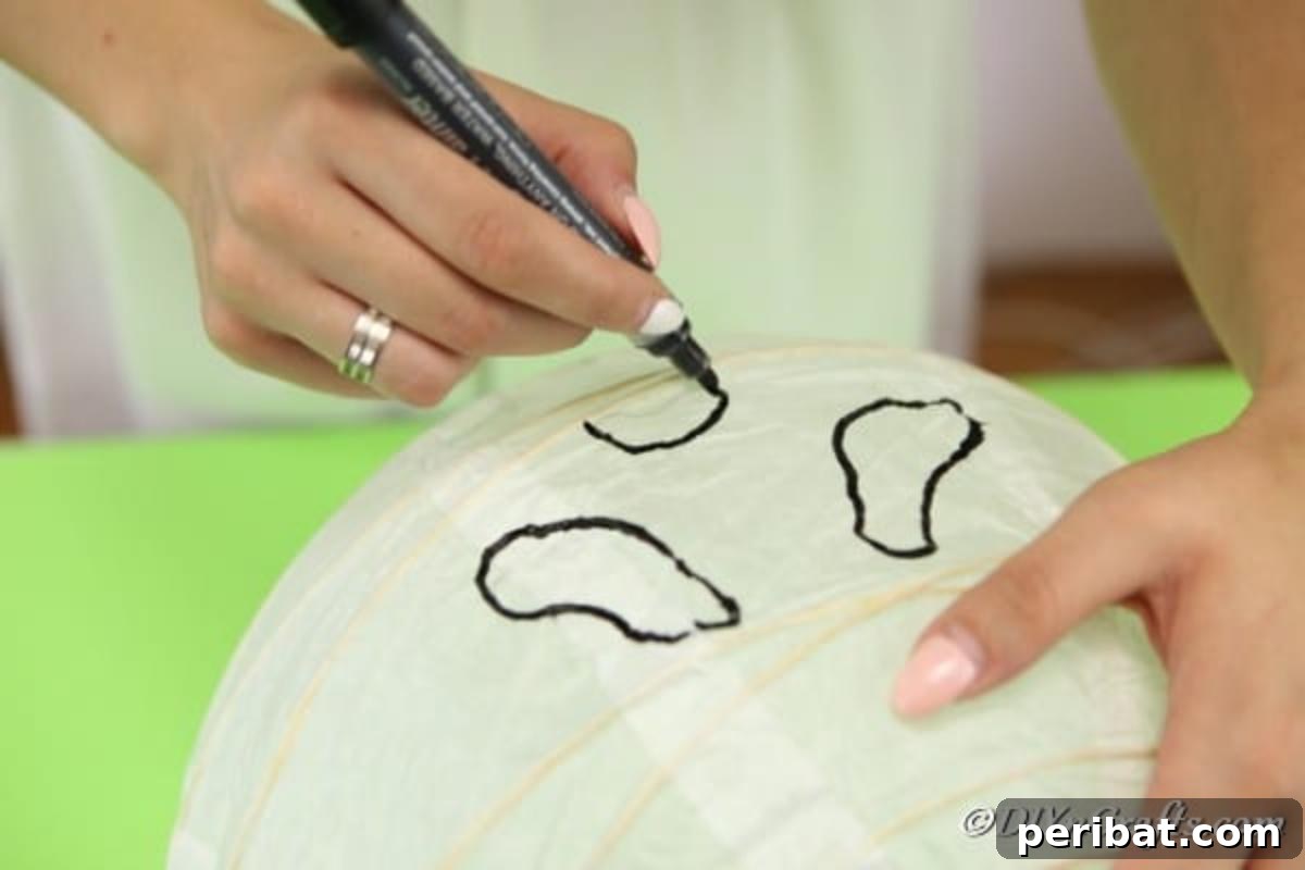 Hauntingly Simple Ghost Lanterns 7 Drawing a face on the ghost paper lanterns with a marker