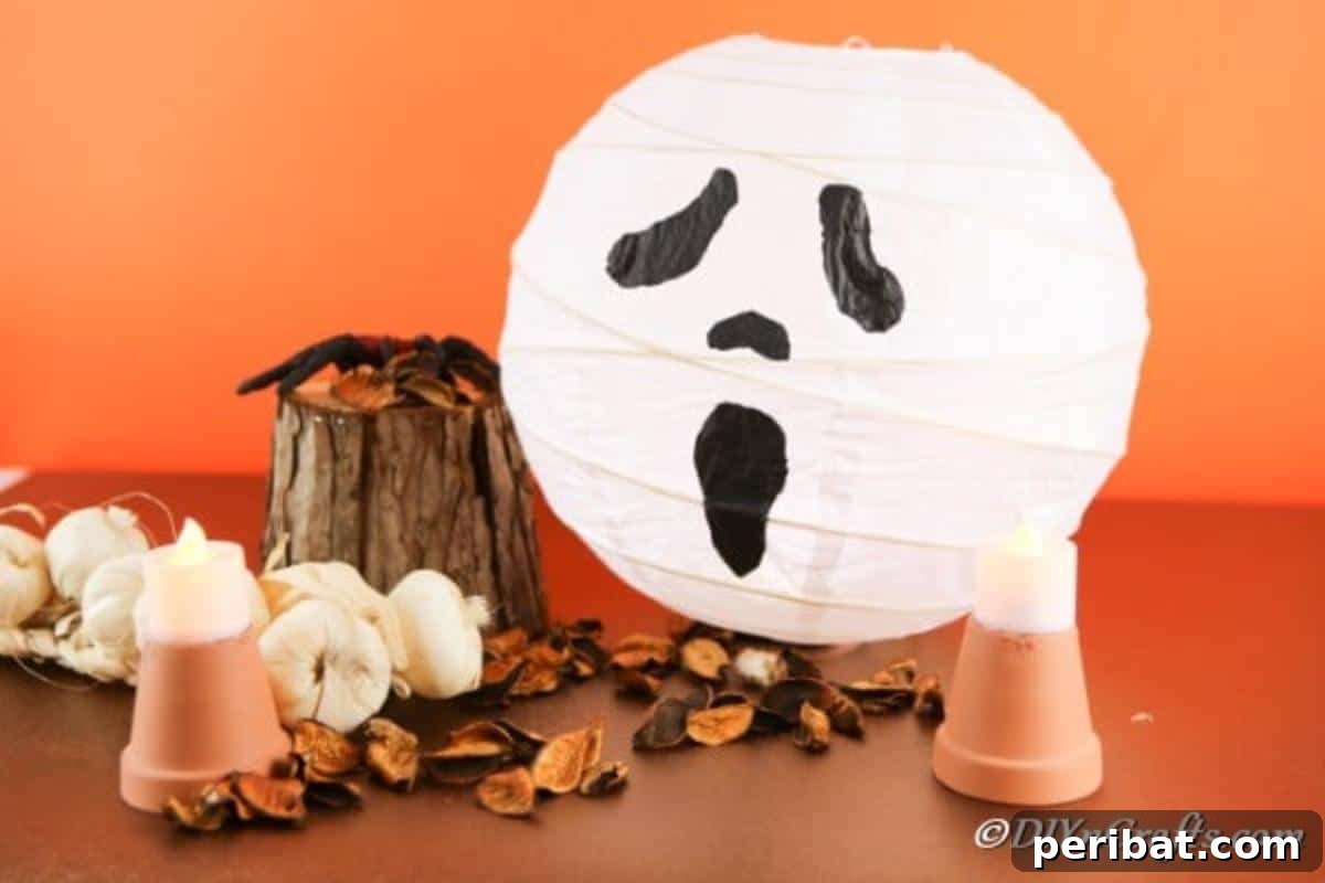 Hauntingly Simple Ghost Lanterns 8 Ghost lantern sitting on a brown table with fall decorations around it