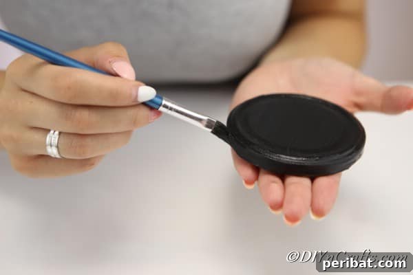 Painting the top of the mason jar lid with black paint