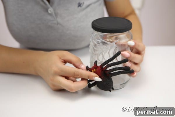 Attaching the plastic spider to the halloween craft jar