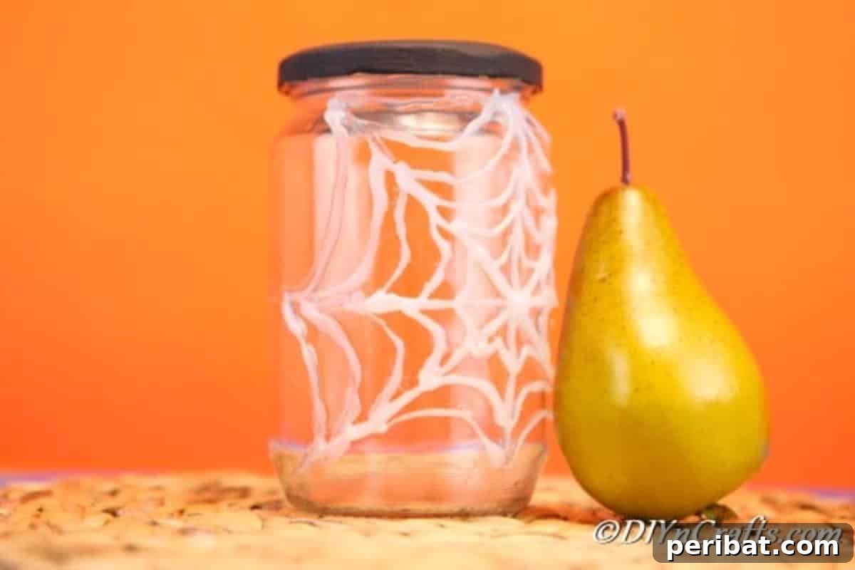 A completed halloween spider web jar sitting on a brown surface with orange background
