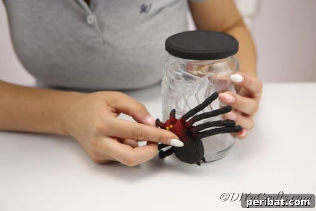 Attaching the plastic spider to the halloween craft jar