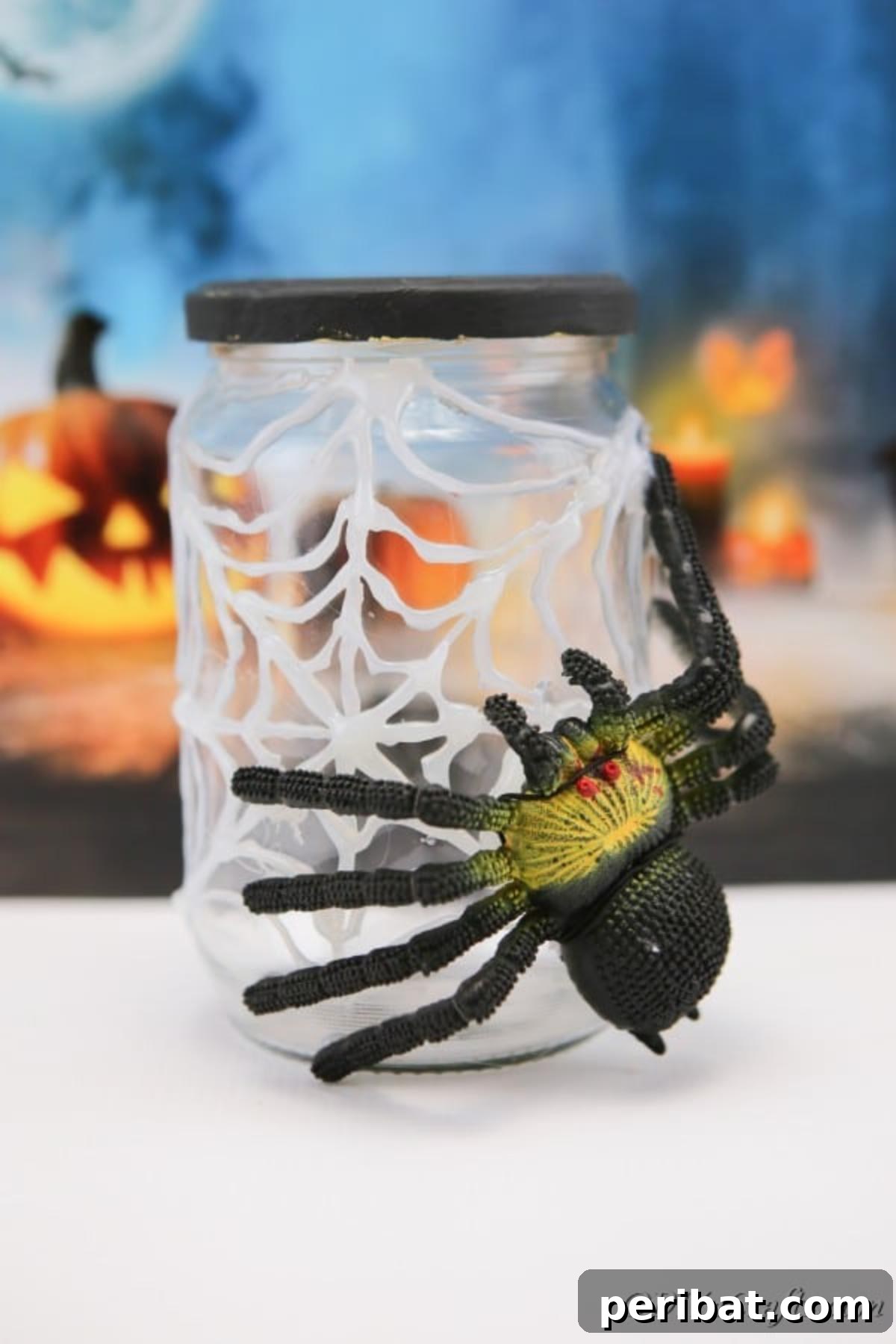 Completed halloween spider jar sitting on white surface with blue halloween themed background