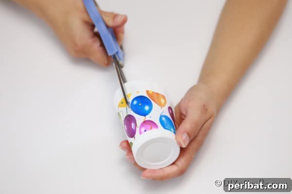 Cutting slits down the side of a plastic cup to create homemade cookie boxes