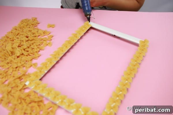 Adding pasta to a picture frame with hot glue