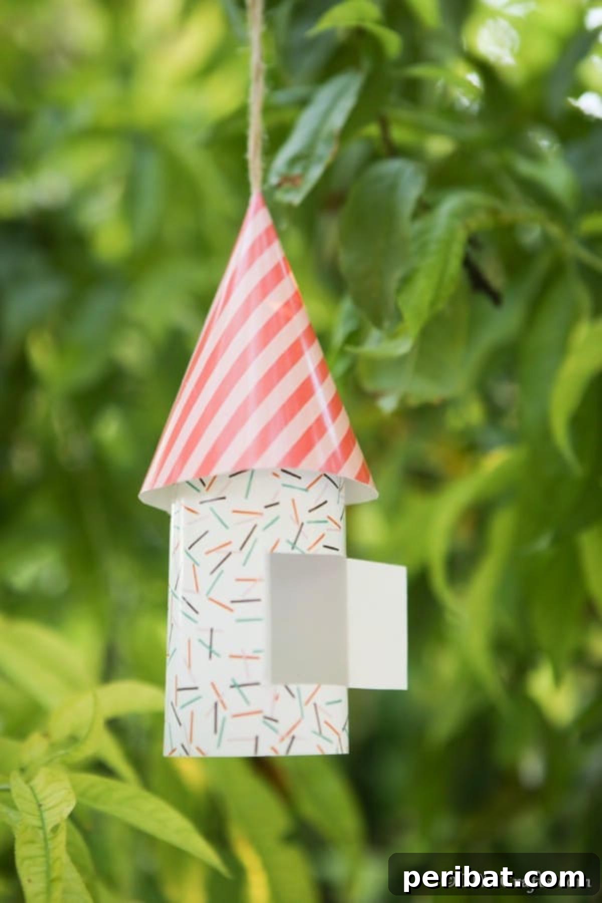 Enchanting Paper Gnome Homes for Your Garden 6 Close-up of a striped paper gnome house hanging from a tree branch, highlighting detail