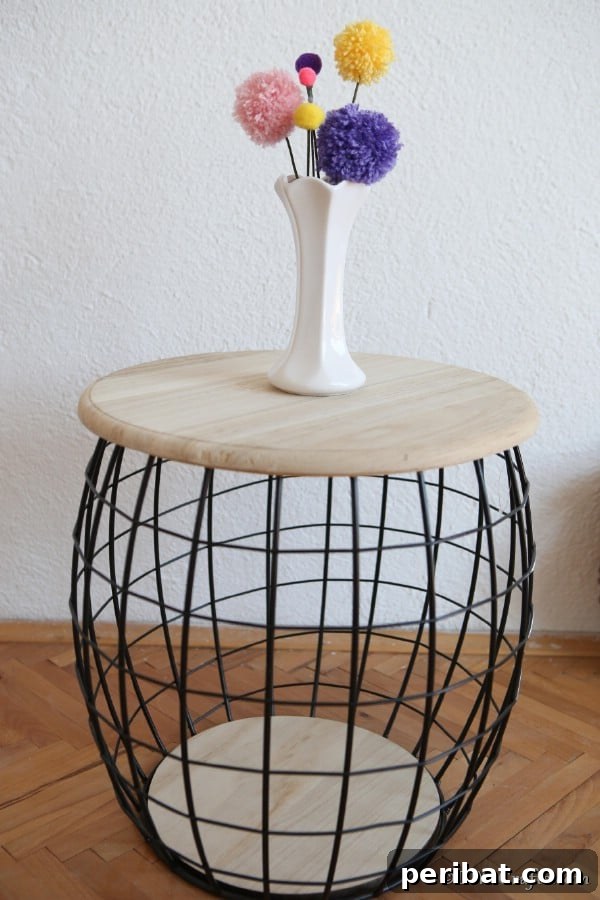 A vase filled with pom pom flowers on a small wooden and wire stool