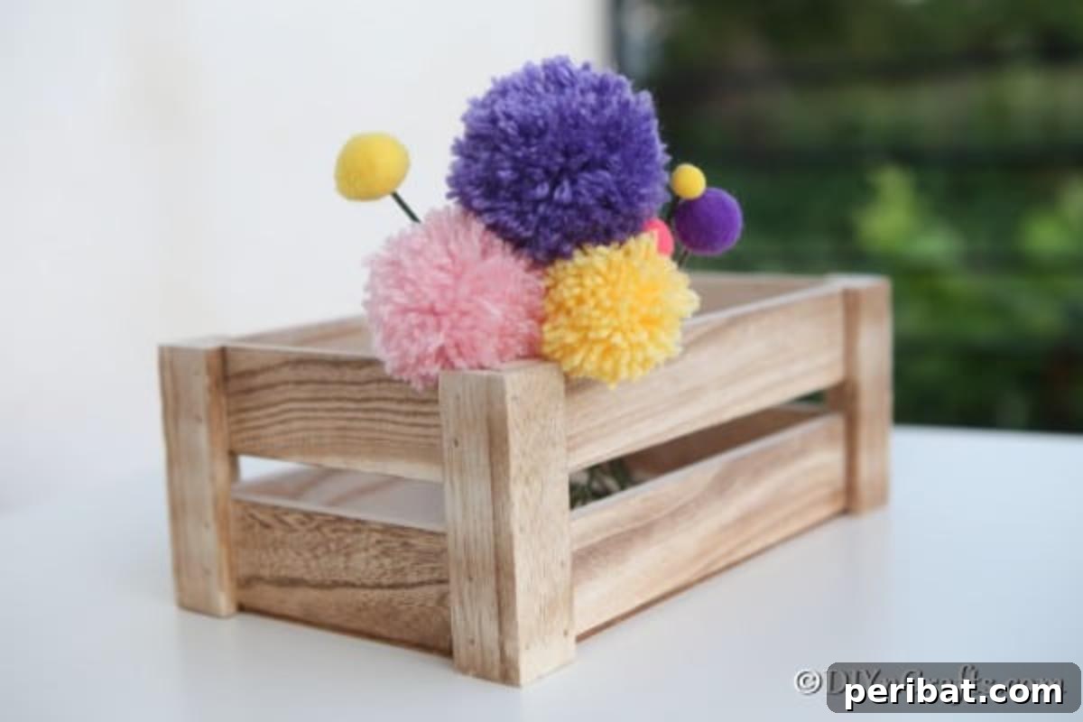 A rustic wooden box, elegantly placed on a kitchen counter, brimming with an assortment of colorful yarn pom pom flowers, creating a cozy display.