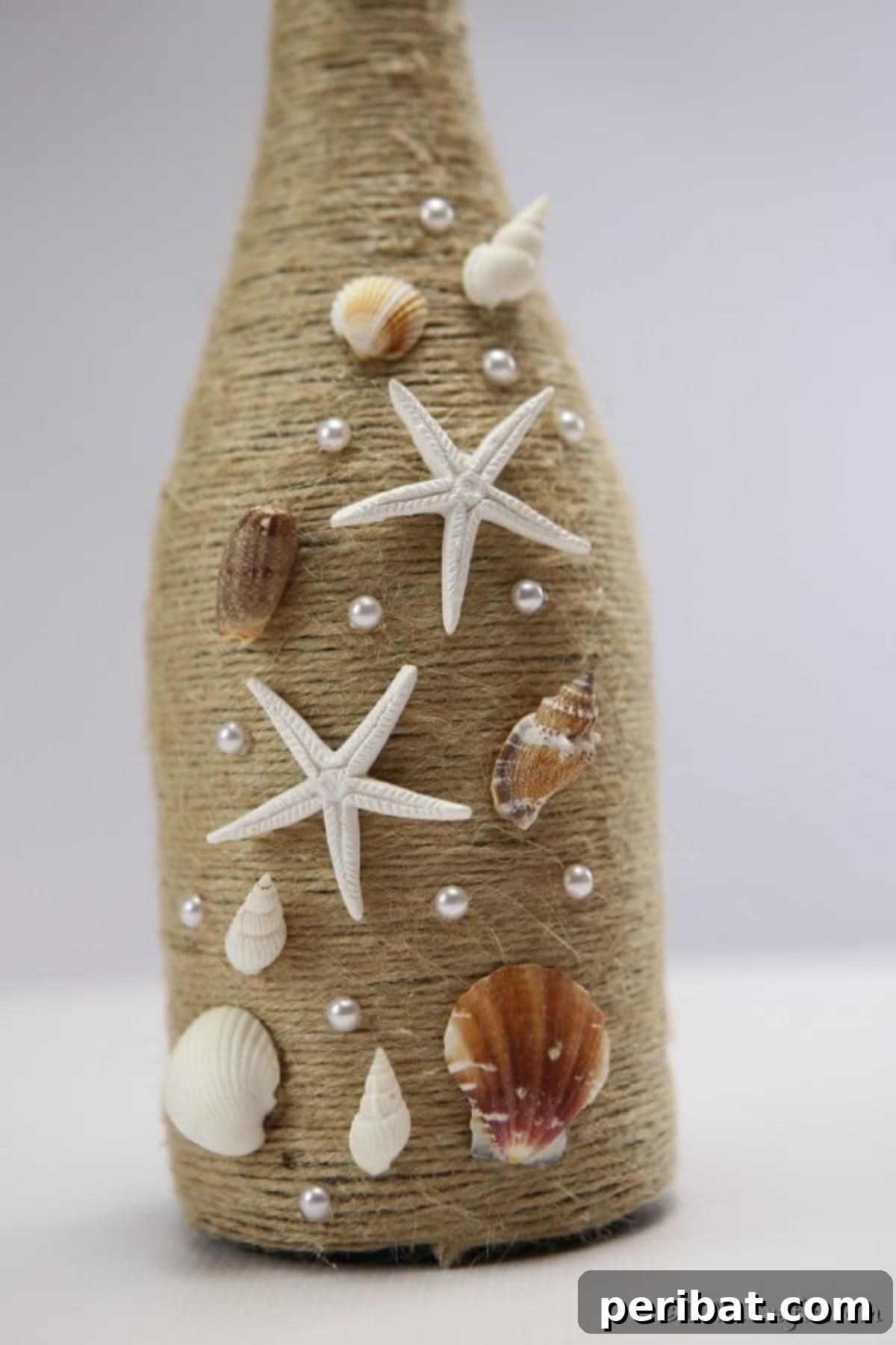 Coastal Rustic Wine Bottle Charm 4 Close-up detail of seashells and twine meticulously attached to a nautical wine bottle decor piece, showcasing the intricate texture.