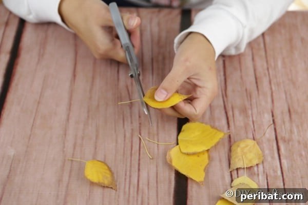Trimming leaves for fall lantern craft, showing preparation before gluing