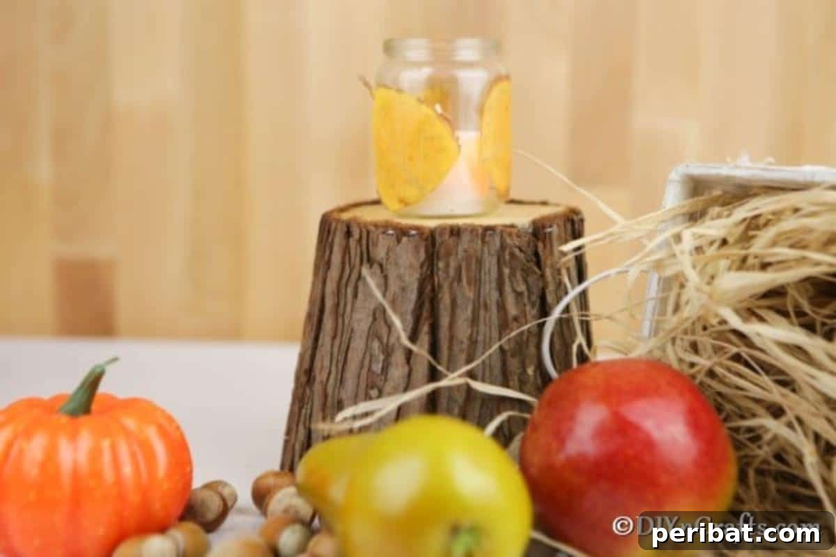 A single fall leaf candle lantern sitting on a small wooden stump, surrounded by other autumnal decorations like mini pumpkins and pinecones