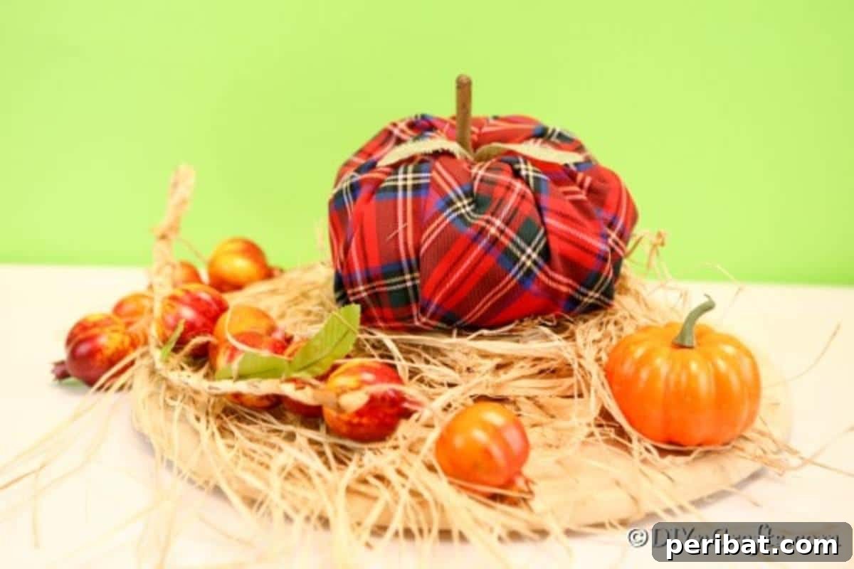A beautifully crafted fabric pumpkin with a plaid pattern, nestled amongst straw and mini pumpkins, set against a verdant green backdrop, exuding rustic autumn charm.