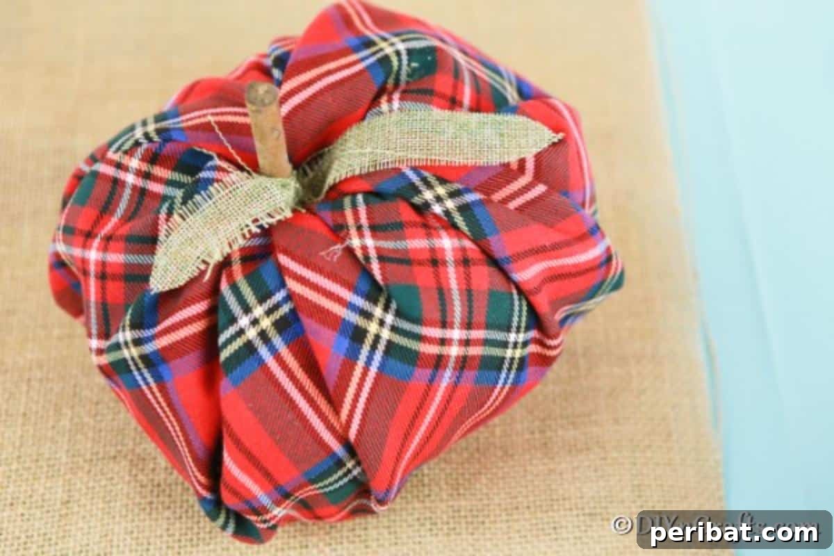 A warm, inviting fabric pumpkin with a soft texture, displayed on a rustic wooden surface, highlighting its handmade charm.