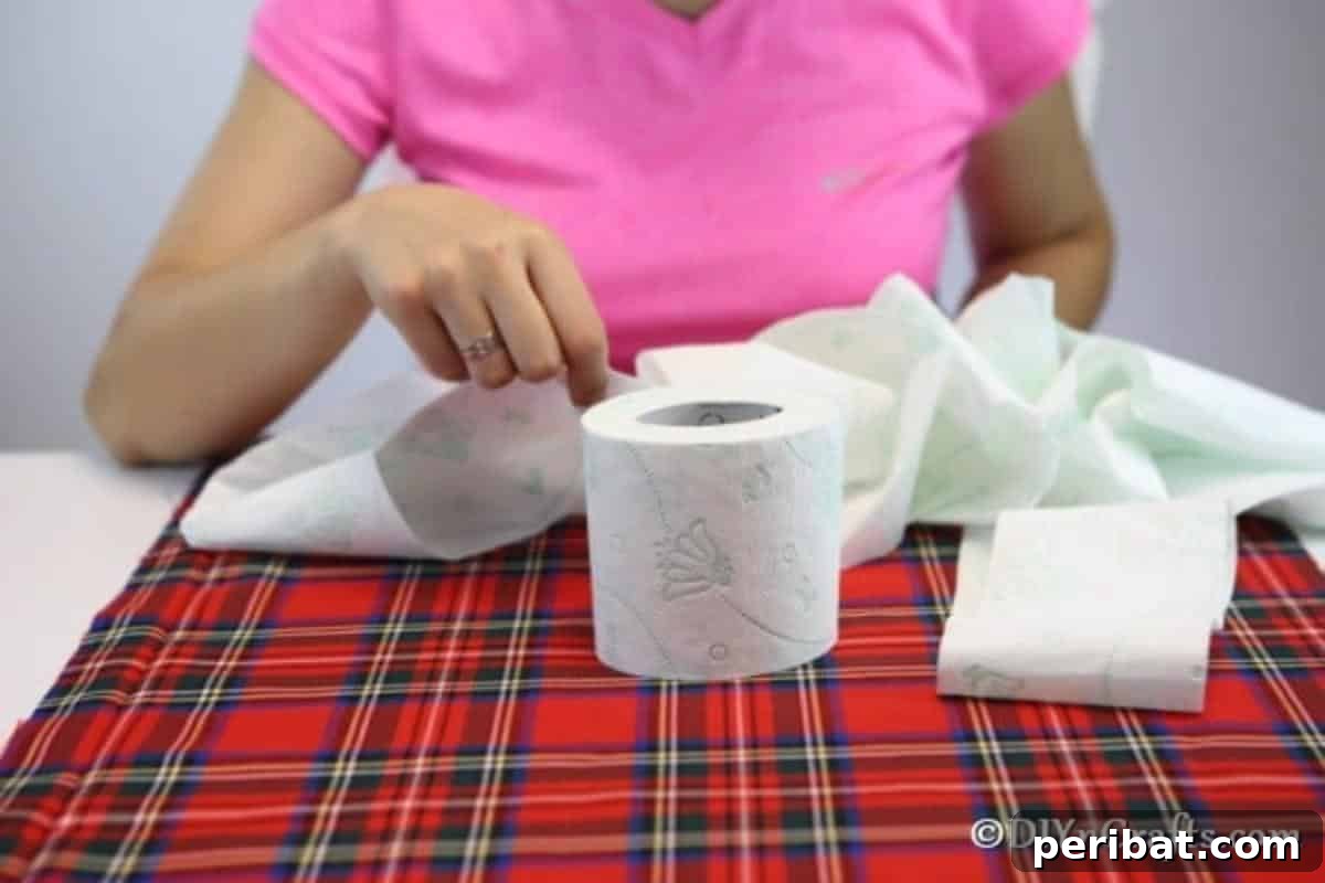 Unwrapping a toilet paper roll to create a soft, fluffy core for the fabric pumpkin.