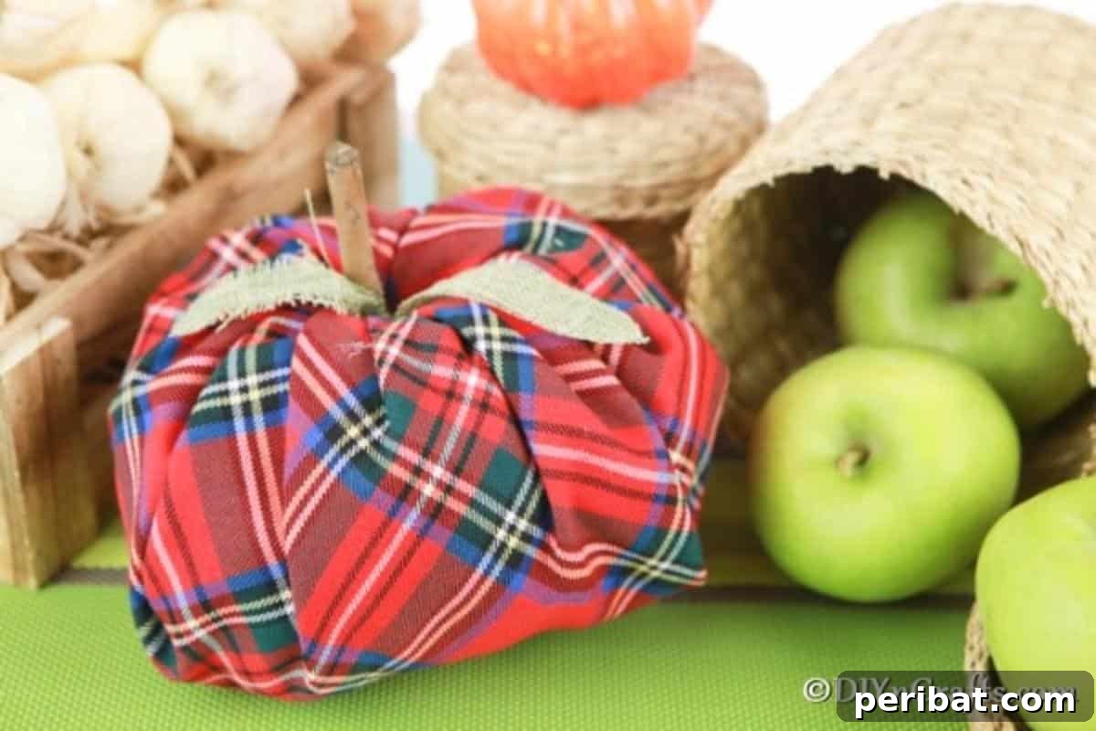 Close-up of a completed fabric pumpkin displayed next to apples and small gourds, showcasing its detailed stem and the warm ambiance it creates.
