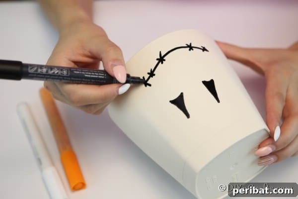 Whimsical Scarecrow Pot Lantern 14 Drawing a face on the clay pot to create a scarecrow