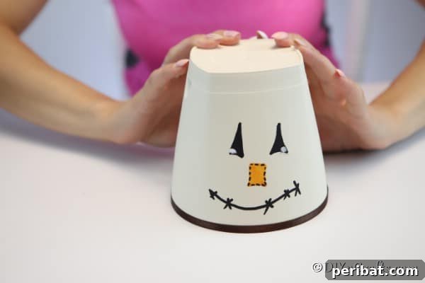 Whimsical Scarecrow Pot Lantern 16 A clay pot with a DIY scarecrow face painted and ribbon added around the bottom