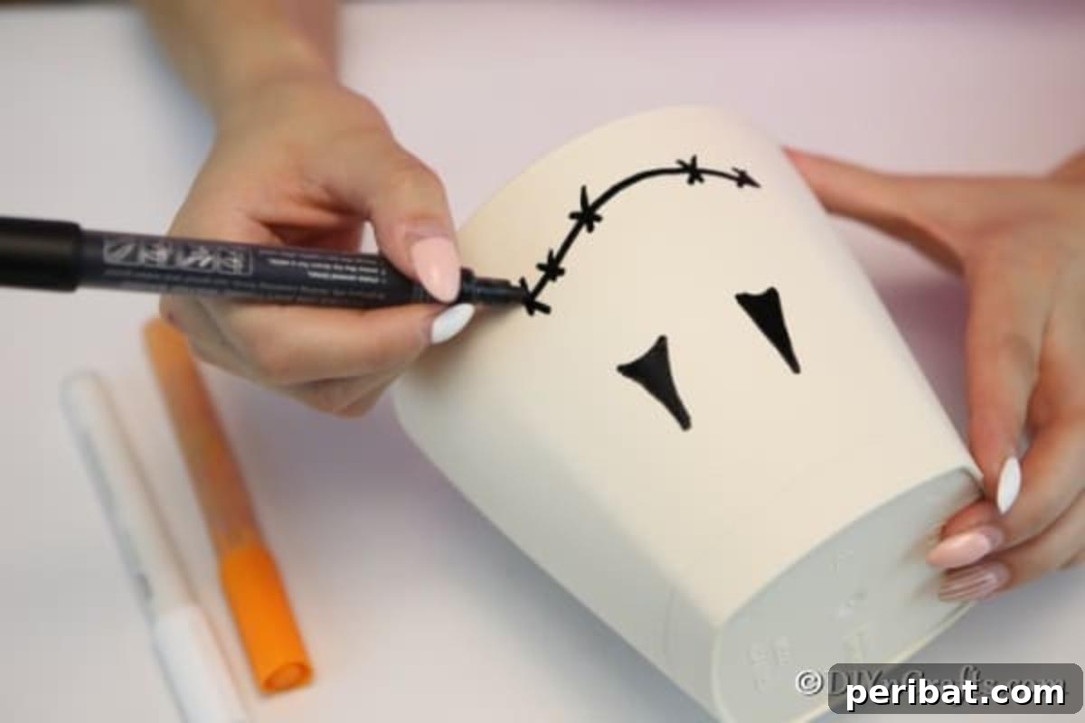 Whimsical Scarecrow Pot Lantern 8 A hand gently sketching the outline of a scarecrow face, including triangular eyes and a square nose, onto a white clay pot, marking the beginning of the lantern's transformation.